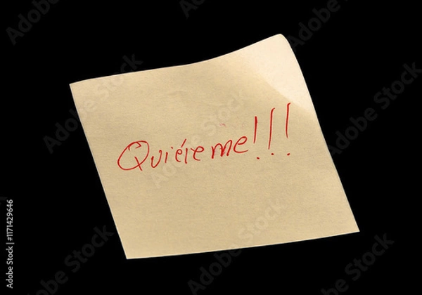 Fototapeta Yellow adhesive paper, similar to a Post-it note, on a black background with the words “Quiéreme” “Love me” in Spanish handwritten in red ink.