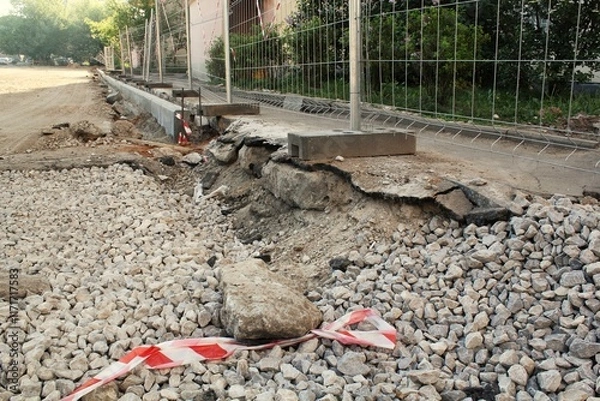 Obraz Part of sidewalk is under construction with the concrete broken and exposed. Area is cordoned off with caution tape and surrounded by rubble. Section of city sidewalk is torn up and under construction