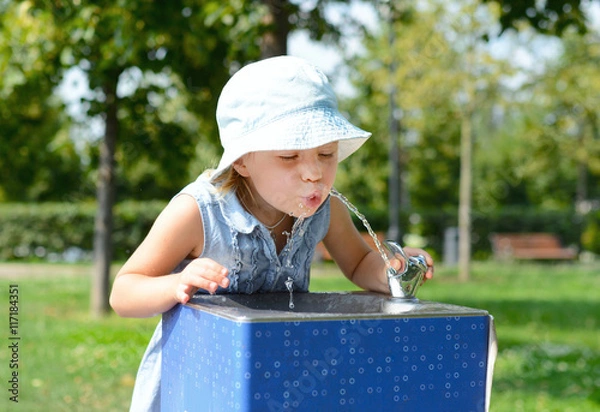 Obraz Cute baby girl drinking from water drinking fountain in summer