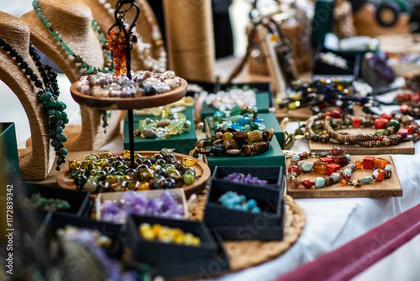 Fototapeta display of handmade jewelry with colorful gemstone necklaces and beads arranged on wooden trays and stands. The collection features an array of textures and hues, showcasing artisan craftsmanship.