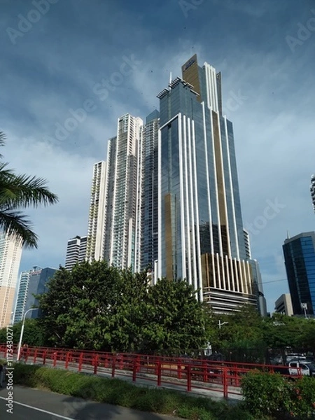 Fototapeta group of tall buildings seen from below, with blue sky in the background and a pedestrian walkway at the bottom
