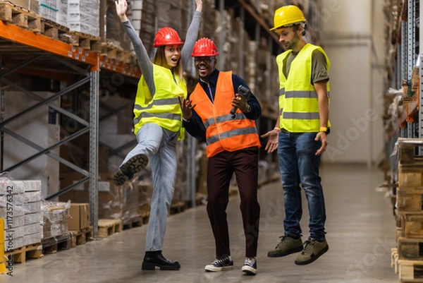 Fototapeta Group of warehouse workers celebrating teamwork and success with cheerful expressions