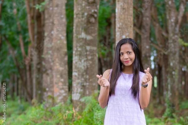 Fototapeta A young beautiful Filipino woman is making a finger heart gesture popularized by Korean K-pop culture
