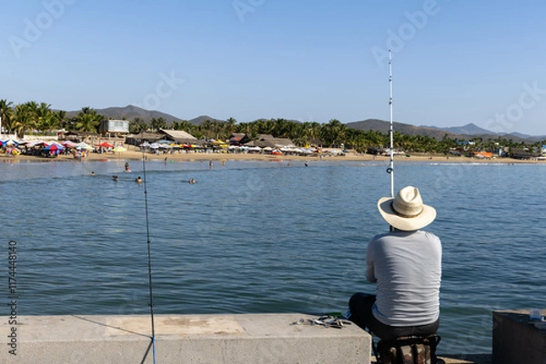 Fototapeta Panorama of the beach in Jalisco, Mexico in which a fisherman can be seen catching fish from the beach boardwalk