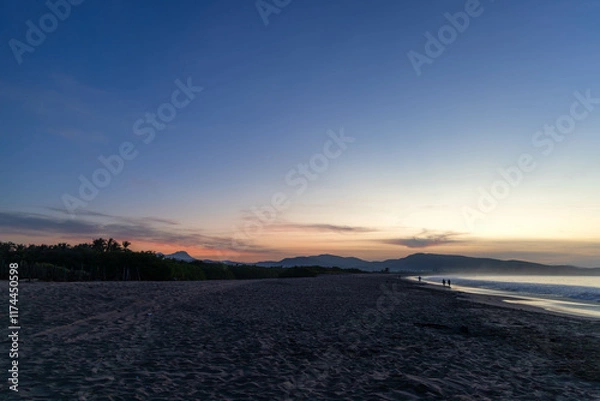 Fototapeta Panorama of beach in Jalisco, Mexico with sunrise while there are people enjoying the beach, playing, running, watching the sunrise