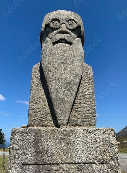 Fototapeta Symmetric view of a statue of a poet with a long beard and glasses, captured on a clear sunny day.