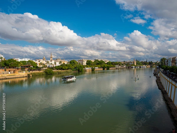 Fototapeta The Canal de Alfonso X111 in Seville, Spain from the Puente de Triana bridge looking towards the Cathedral and La Giralda belltower. Space for text.