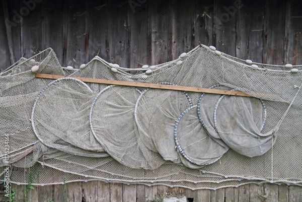 Obraz Fishing nets hang to dry near a boathouse on the lake