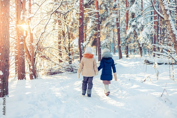 Fototapeta Children walk in a winter snowy forest.