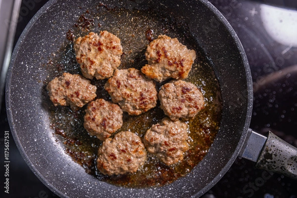 Obraz Perfectly seared burger patties in a frying pan, browned and ready to serve, sitting in flavorful oil.