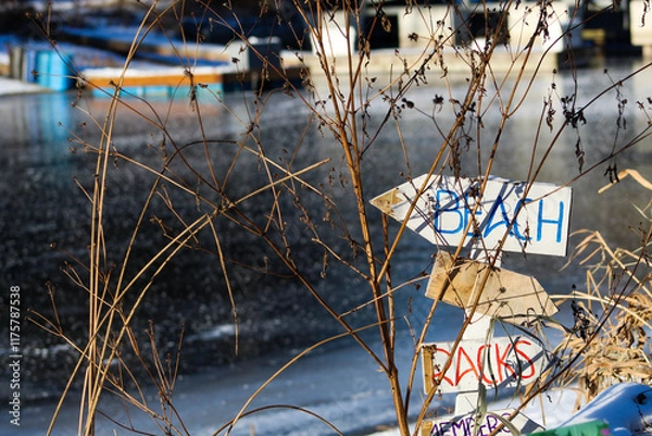 Fototapeta Frozen channel with beach sign and house boats on winter sunny day