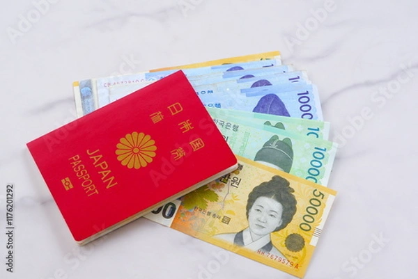 Obraz 韓国の通貨、ウォンKRWの紙幣とパスポート（一般旅券10年用赤色）を用意して、韓国への旅行を計画しているイメージ

