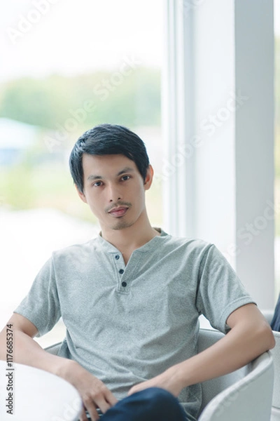 Obraz Young Man Sitting Near Window in Modern Indoor Setting