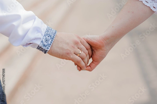 Fototapeta Romantic Moment: A Close-Up of Intertwined Hands with Wedding Ring