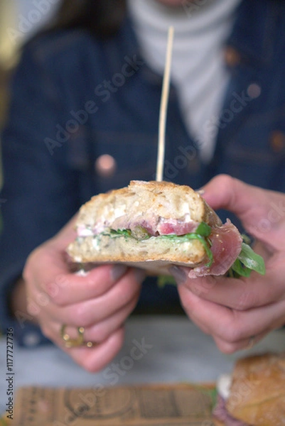 Obraz A detailed close-up of a gourmet sandwich being held in both hands. 