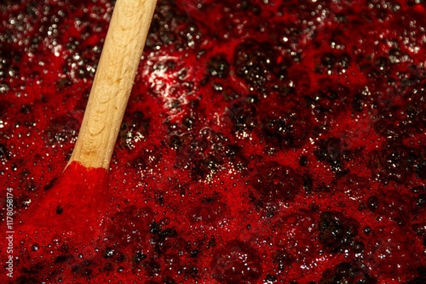Fototapeta close up of blackberry jam boiling with wooden spoon.