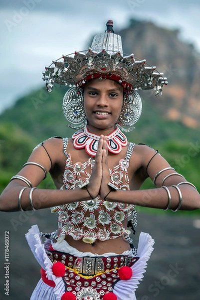 Fototapeta SIGIRIYA, SRI LANKA - JULY 16, 2024 : A Ves Dancer, also known as a Kandyan Dancer or Up Country Dancer performs at Sigiriya in Sri Lanka. In the background stands Sigiriya Rock.