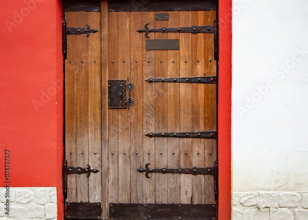Fototapeta Close up of old wooden doors with heavy metal hinges in stone building
