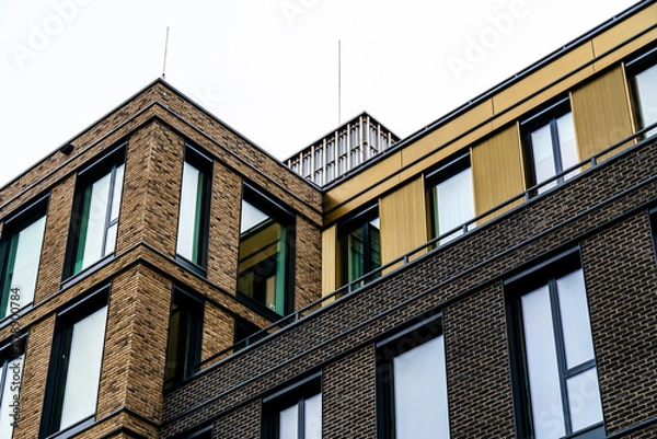 Fototapeta Modern Urban Building with Brick Facade, Large Windows, and Yellow Architectural Accents