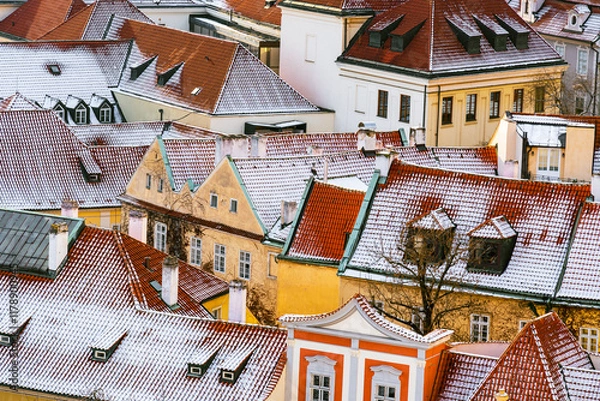 Fototapeta Snow-Covered Rooftops of Malá Strana in Prague with Historic Architecture and Red Tiled Roofs
