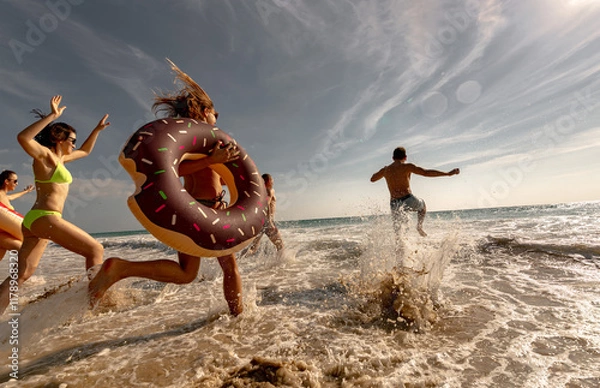 Obraz Big group of happy young friends are having fun, runs and jumps at sunset sea beach. Tropical vacations concept