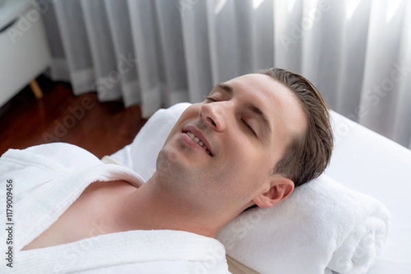 Fototapeta Caucasian man customer enjoying relaxing anti-stress spa massage and pampering with beauty skin recreation leisure in day light ambient salon spa at luxury resort or hotel. Quiescent