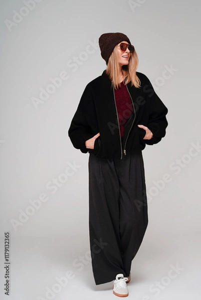 Obraz Trendy woman in stylish spring, autumn outfit looking away and smiling while posing on studio background.