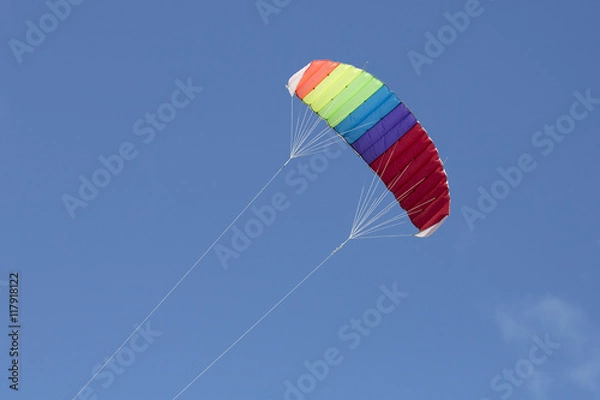 Fototapeta Multi-colored kite flying with a blue sky