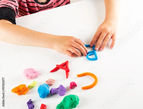 Fototapeta Child hands with colorful clay. Mold letters