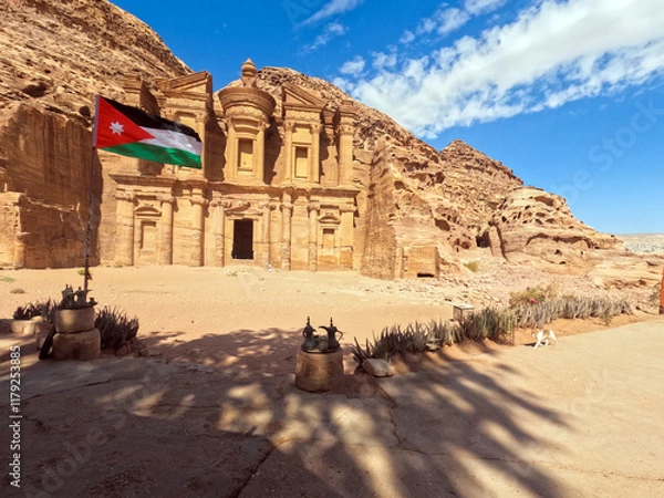 Fototapeta Petra, Jordan : The Jordanian flag flies in front of the ancient Monastery building in Petra (Ad Deir) (one of the Seven Wonders of the World) historical place