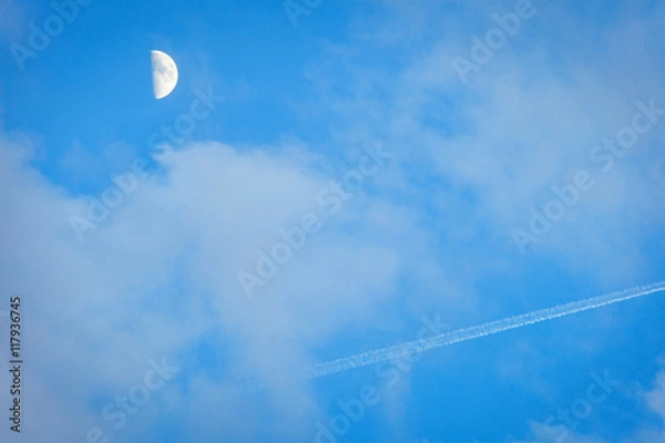Fototapeta The moon and the trace of the plane in the blue sky