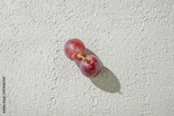 Fototapeta Close up of vibrant red grapes against a textured white background, highlighting their freshness and texture