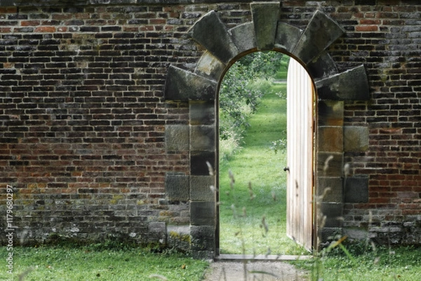 Obraz English wall garden entrance. Invitation to the spring concept. Half opened door into the beautiful summer orchard