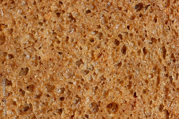 Fototapeta The sourdough brown bread slice in macro view. Texture of natural dark bread with porous for healthy nutrition