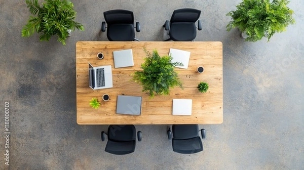 Fototapeta Modern Office Workspace with Wooden Table, Laptops, Green Plants, and Black Chairs in an Aerial View, Ideal for Business and Creative Collaboration