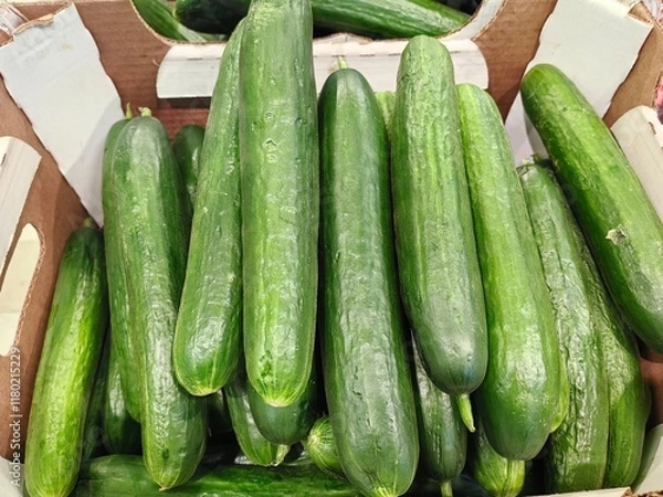 Fototapeta bumpy and smooth cucumbers lie in a box in a store