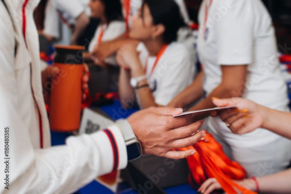 Fototapeta Process of checking in on conference congress forum event, registration desk table, visitors and attendees receiving lanyard with name badge and entry wristband bracelet and register electronic ticket