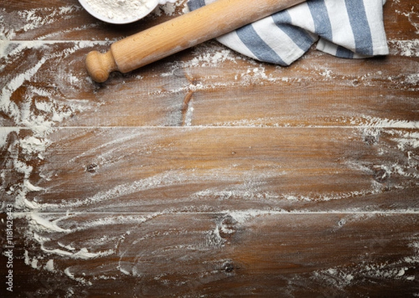 Fototapeta Wooden pastry board with scattered flour, rolling pin and dishcloth, top view, space for text.