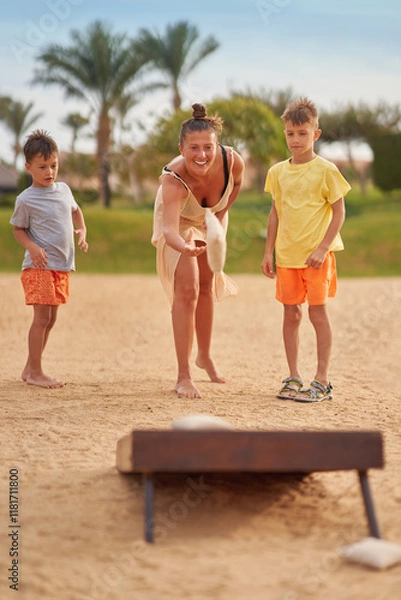 Fototapeta Mother with son plays bean bag game cornhole in Egypt Hurghada