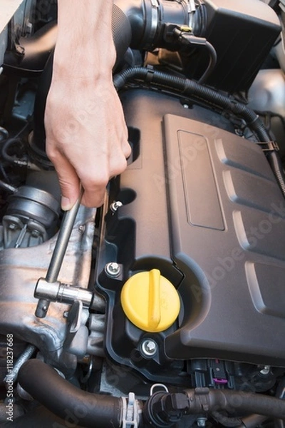 Fototapeta Hand repairing a modern car engine with a wrench