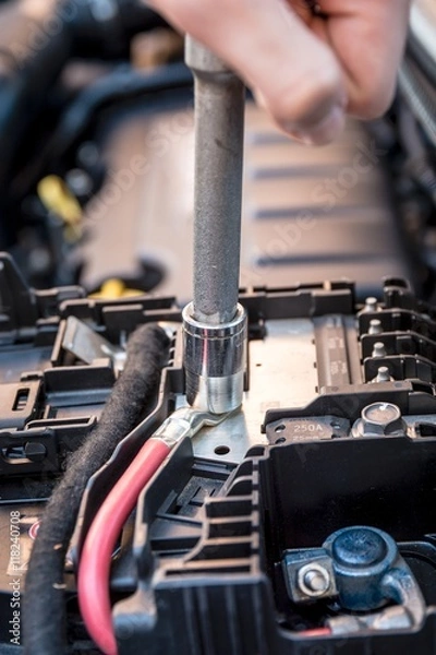 Fototapeta Hand checking the bolt of the battery with a wrench in a modern car engine