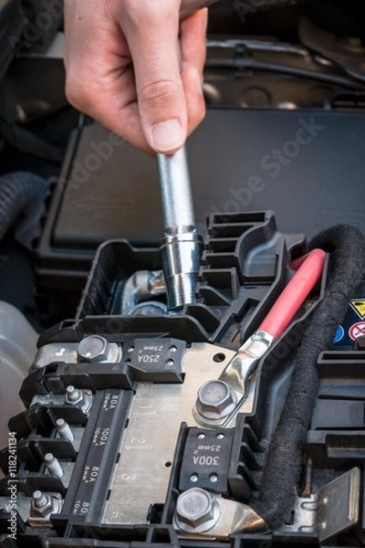 Fototapeta Hand checking the bolt of the battery with a wrench in a modern car engine