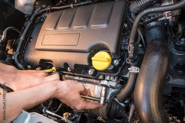 Fototapeta Hands repairing a modern car engine with a wrench