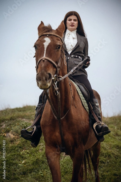 Fototapeta A person riding a horse in a field