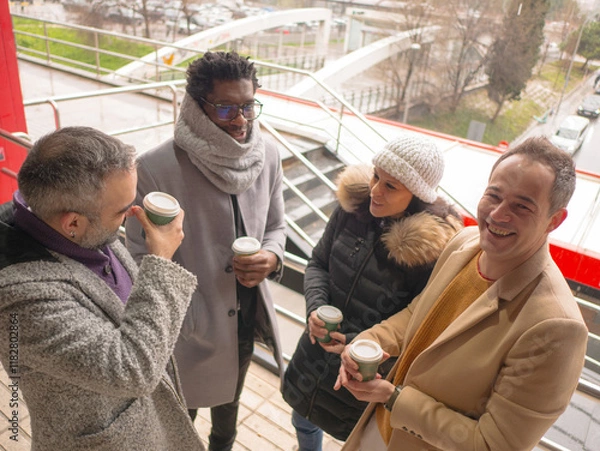 Fototapeta Four office workers on a coffee break in a busy business district. One Black male, a woman, and two Hispanic individuals are standing together. Only one of them, a Hispanic man, looks directly at the