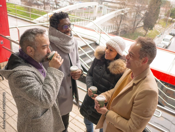 Fototapeta Four office workers taking a coffee break in a lively business district. The group consists of one Black male, a woman, and two Hispanic individuals. They are looking at each other and engaging in