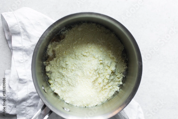 Fototapeta Overhead view of powdered milk in a saucepan, top view of full fat milk powder in a pot