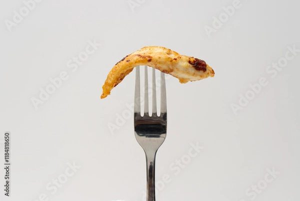 Fototapeta Piece of fried chicken skewered on a fork. Food close-up on white background, copy space