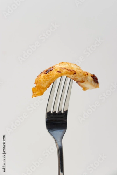 Fototapeta Piece of fried chicken skewered on a fork. Food close-up on white background, copy space