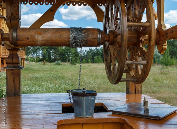 Fototapeta Wooden well with a large collar and iron bucket on a chain, the Russian village